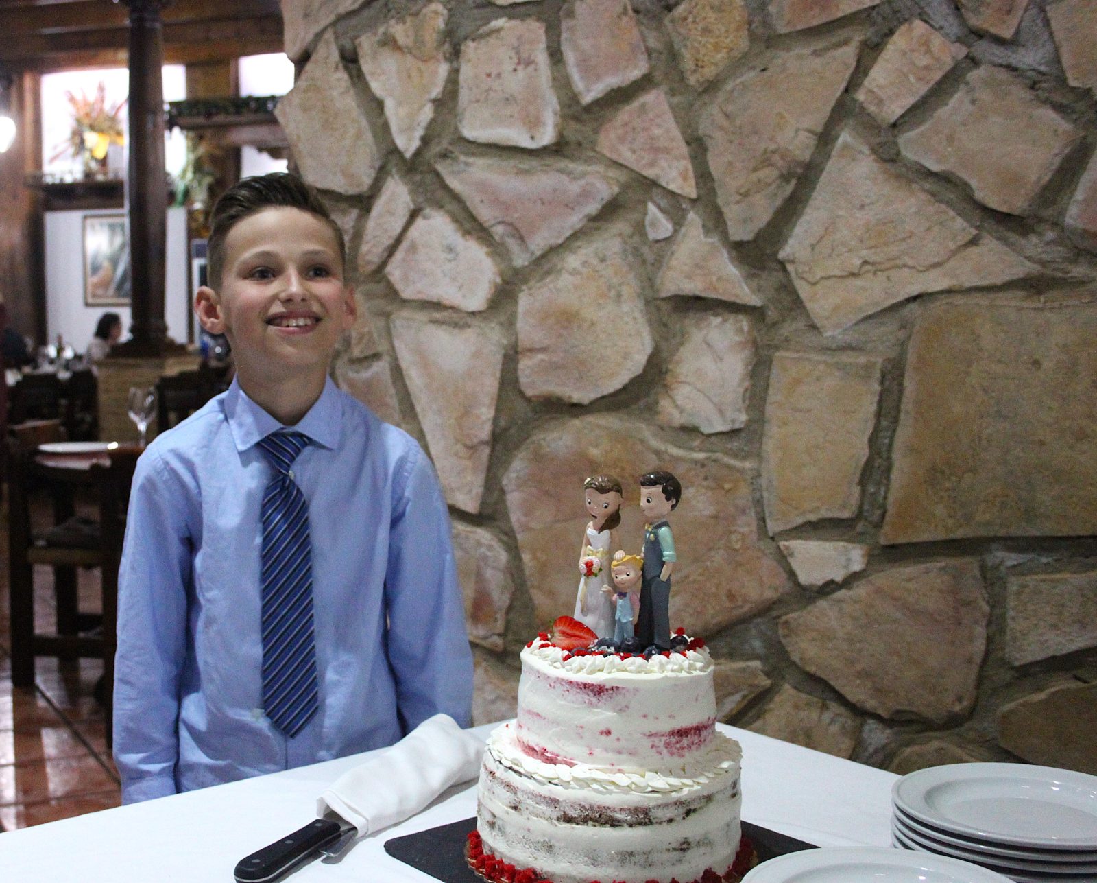O menino, feliz junto ao bolo de casamento